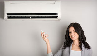 Woman holding remote control to Ductless Air Conditioning system